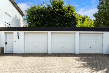 Parking garage in residential house for cars with white block doors in sunny day.