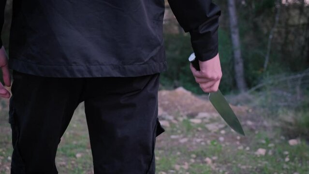 A man with a knife in the forest. The maniac pursues the victim and prepares to attack