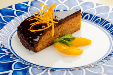 Orange, sponge cake under chocolate frosting. On a white background, isolated.