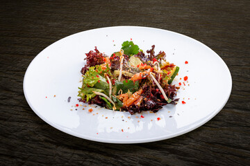 Salad with crispy salmon belly and flying fish roe. On a dark background, isolated.