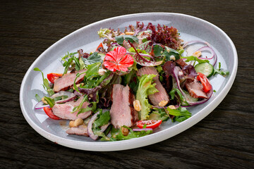 Josper-oven veal salad with sauce. On a dark background, isolated.