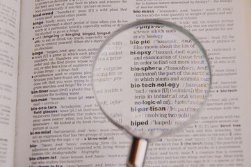 The definition of the word Biotechnology in a dictionary, under magnifying glass, translator and...