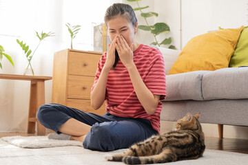 Asian young woman, girl hand in sneezing from fur allergy while playing with her lovely cat, pet on...