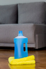 Floor cleaner in a plastic bottle and a floor cloth on the parquet floor indoors. House cleaning