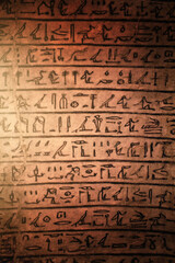 Fototapeta na wymiar Egyptian hieroglyphs on a sandstone slab in the rays of the evening sun.