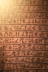 Fototapeta na wymiar Egyptian hieroglyphs on a sandstone slab in the rays of the evening sun.