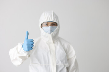Woman in protective respirator and white coverall showing thumb up sign