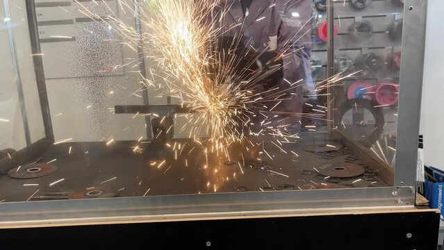 Hot sparks of metal. Cutting by a worker of a metal workpiece with a disk with diamond grit.