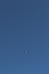 A beautiful image of a white airplane flying in a cloudless blue sky.