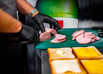 chef hand cooking sandwich with ham, cheese and vegetables on kitchen
