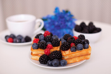 Morning breakfast with cup of tea, waffles and berries
