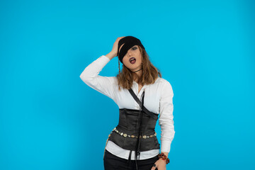 Fototapeta premium Young pretty pirate girl stand on blue background