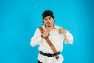 Young handsome pirate stand on blue background and looking at camera