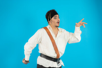 Young joyful pirate dancing on blue background
