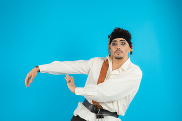 Handsome young pirate dancing on blue background.