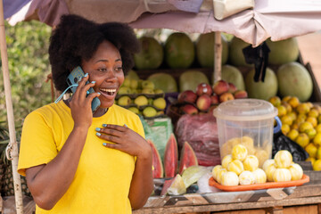 african lady in a market making a phone call excitedly