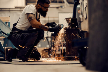 A metal workshop worker grinding metal parts in facility.