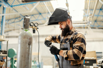 A metallurgy worker preparing welder for work in factory. - obrazy, fototapety, plakaty