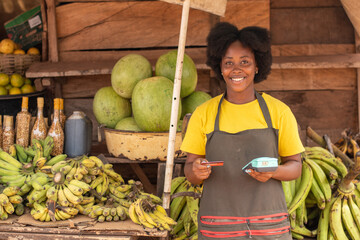 african market woman holding a pos device and a credit card