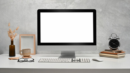 Front view computer with empty display, picture frame, books and alarm clock on white table
