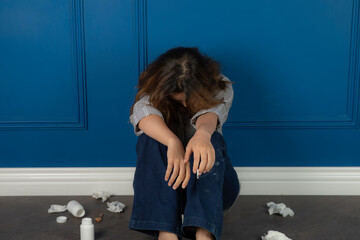 A young depressed girl sitting on the floor and crying.