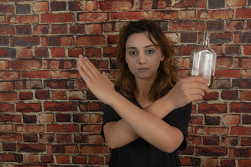 Young girl holding alcohol and crossed her hands.