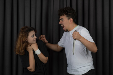 Young angry man attacking a girl with a knife