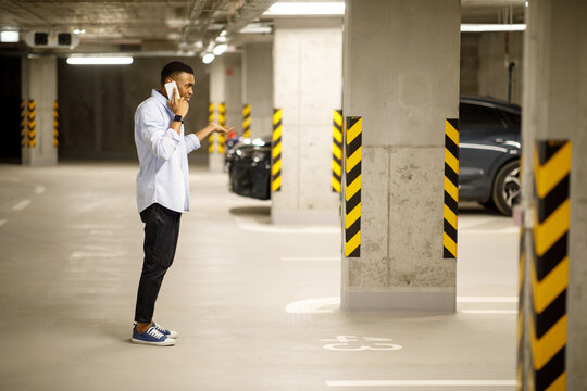 The man found his car missing. Angry African American talking about a missing car on the phone. Car theft concept