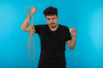 Crying addicted male holding inject and rope.