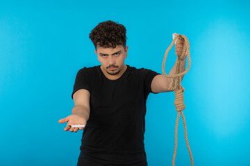 Young male holding inject and rope. Thinking about suicide