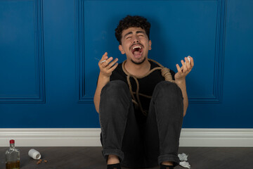 Young man smoking and crying while sitting on the ground