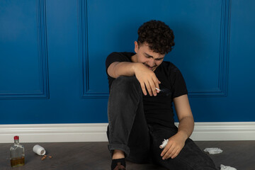 Crying man sitting on the ground and smoking