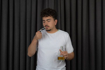 Young man holding bottle of alcohol and smoking.