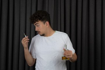 Addicted man holding bottle of alcohol and looking at injection.