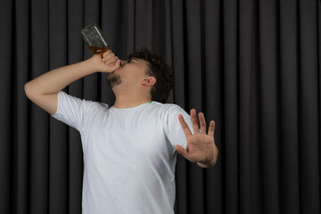 Young man drinking alcohol and gesture stop