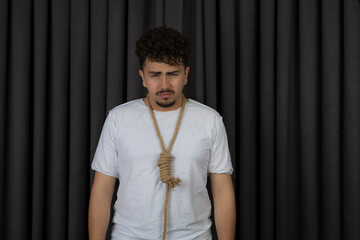 Portrait of depressed guy hang rope around his neck and looking at camera