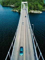 Aerial view of modern suspension bridge with car or truck over the blue lake water in Finland