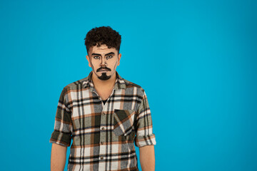 Young man with pop art makeup stand on blue background.