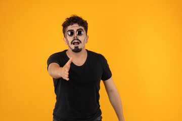 Young creative man wears sunglasses and point his hand to the camera