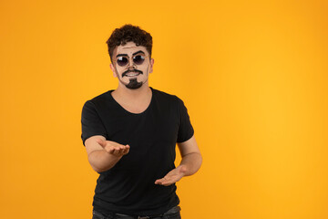 Young man with sunglasses stands on orange background