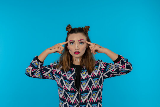 Portrait of young beautiful girl with creative makeup holding her fingers to her head.