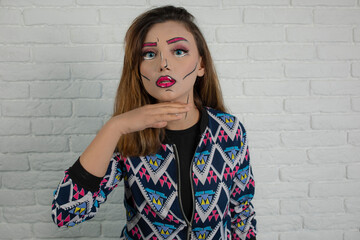 Portrait of young girl wearing creative makeup and holding her hands to her neck