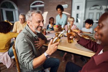 Happy man toasting with his black father in law during family lunch on patio.