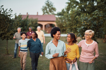 Happy multiethnic family enjoys while taking a walk in their backyard.