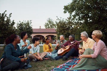 Happy multiracial extended family enjoying in drinks and acoustic music in backyard.