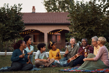 Happy multi-ethnic extended family enjoying in sounds of acoustic music in backyard.