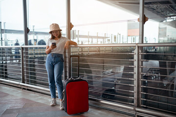 Traveler with suitcase in airport concept.Young girl using smartphone with carrying luggage and...