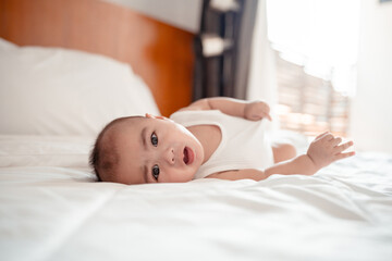 Obraz na płótnie Canvas Smiling of newborn baby or cute little lying on a white bed at home. Infant child portrait happy concept, Healthy childcare in the morning.