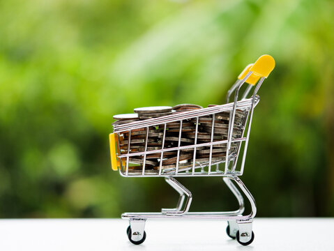 Money cart for money saving concept. Coin in the shopping cart on white table, nature background.
