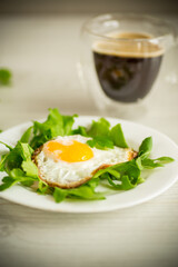 one fried egg with arugula and lettuce in a plate